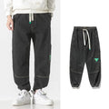 Men's loose-fit cotton tapered trousers in grey shown flat.