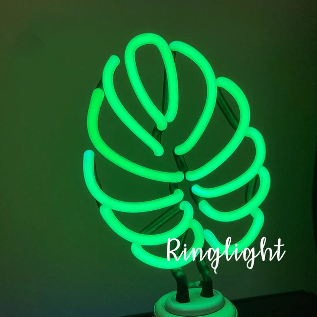 Minimalist white bamboo-shaped desk lamp emitting a soft green glow from its tube.