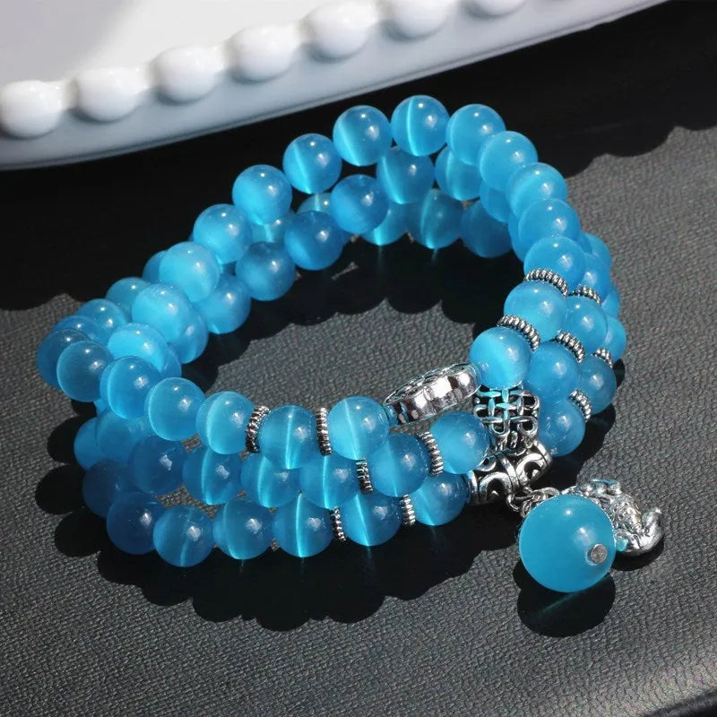 Women's opal bracelet with three interlocking rings, a Lucky Cat charm, and geometric stones in various colours.