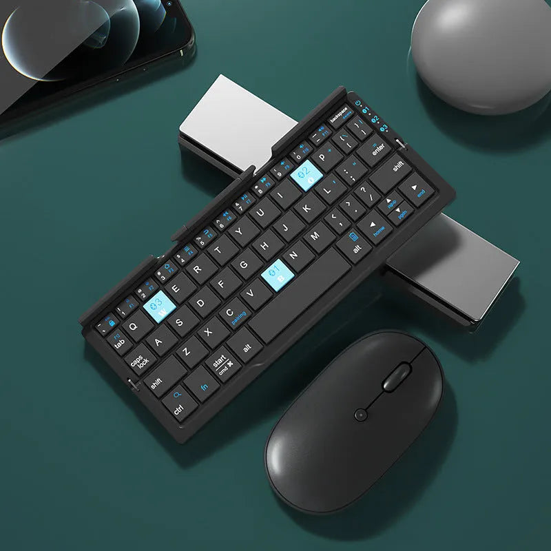Silver white aluminium folding Bluetooth keyboard shown open next to a smartphone propped on its hidden stand.