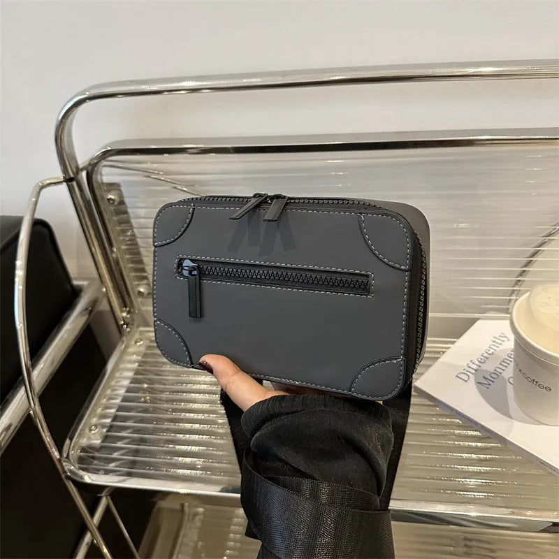 A small, square, structured crossbody bag in a choice of colours, showing its horizontal shape and sewing line detailing.