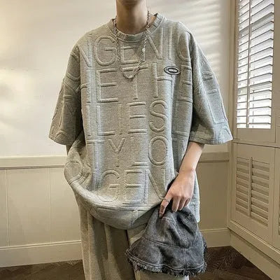 Men's grey loose-fit t-shirt with a raised retro letter print on the chest.