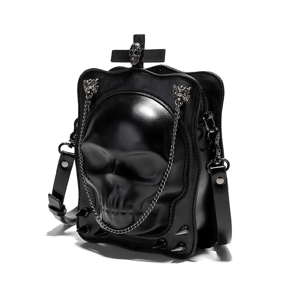 Black vertical square crossbody bag with embossed skull design, chain strap, and metal rivets.