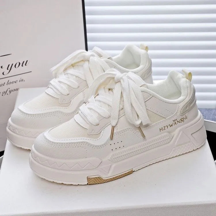 Beige children's lace-up trainers with cross straps over foot and thick rubber platform sole.