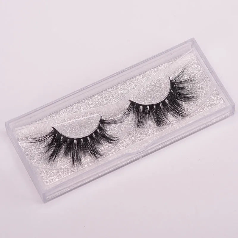 A pair of black 5D false eyelashes made from mink hair with an application brush and storage cap.