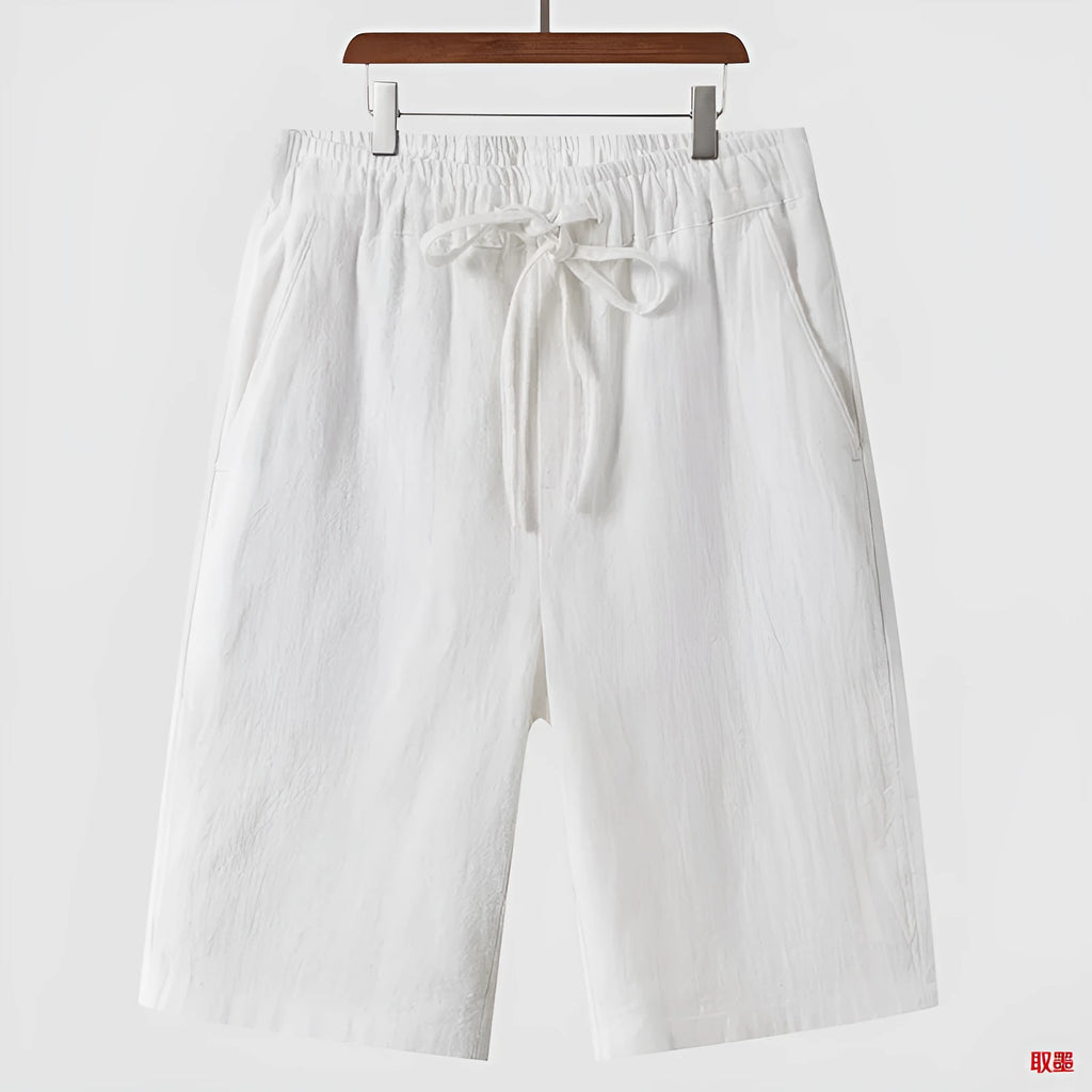 Man wearing beige linen loose-fit cropped shorts on a summer day.