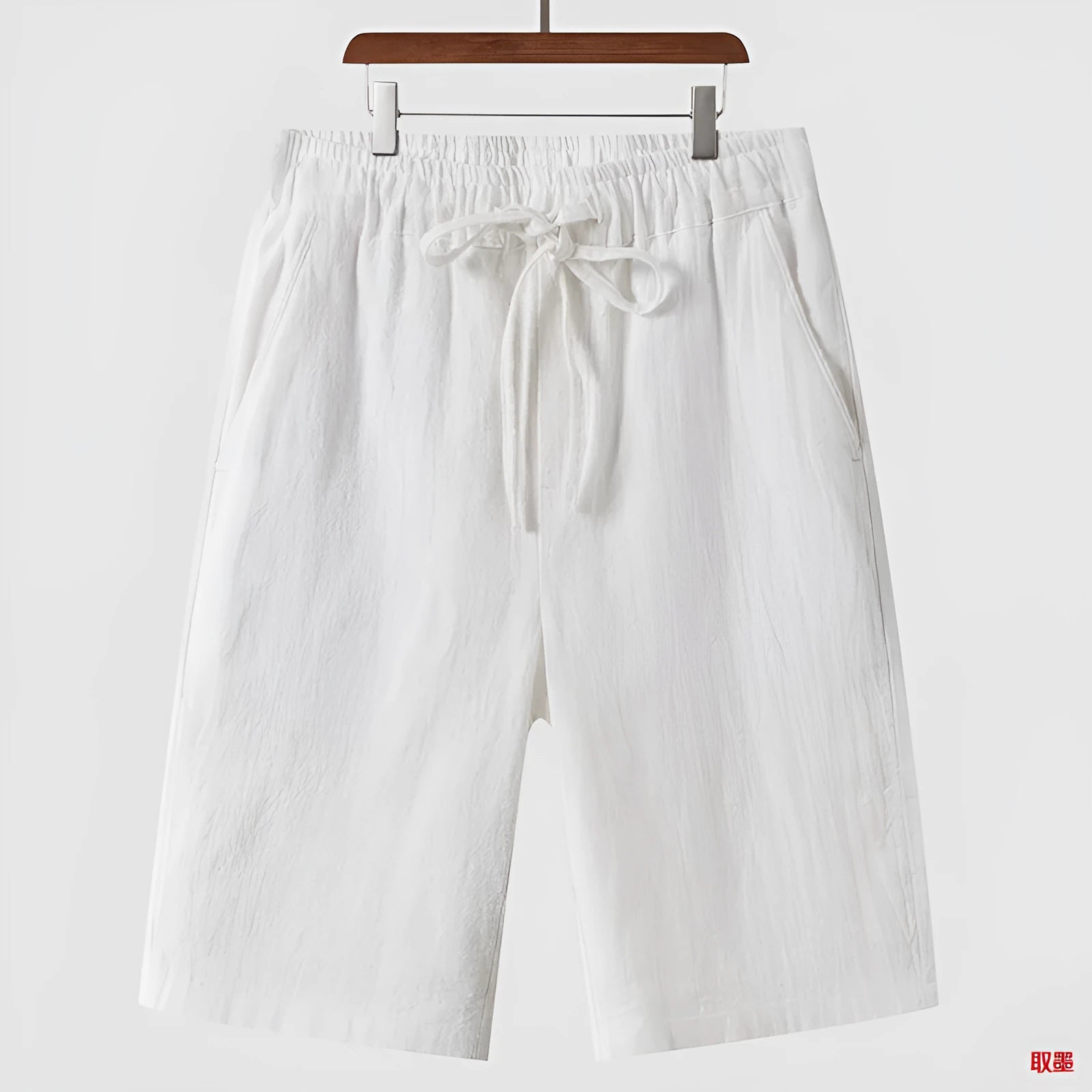 Man wearing beige linen loose-fit cropped shorts on a summer day.