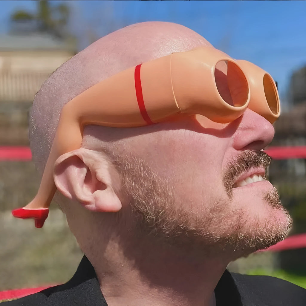 Orange plastic novelty sunglasses shaped like a pair of legs, on a white background.