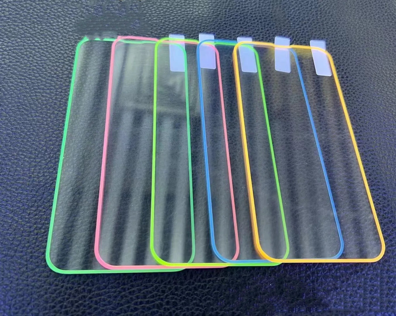 Fluorescent pink tempered glass screen protector applied to an iPhone 13 Pro, glowing softly on a dark background.