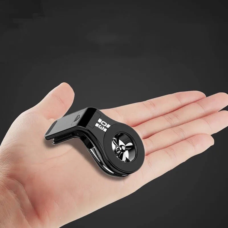 Black magnetic car phone holder clipped to a car air vent, showing a smartphone attached and the 360-degree rotating bracket.