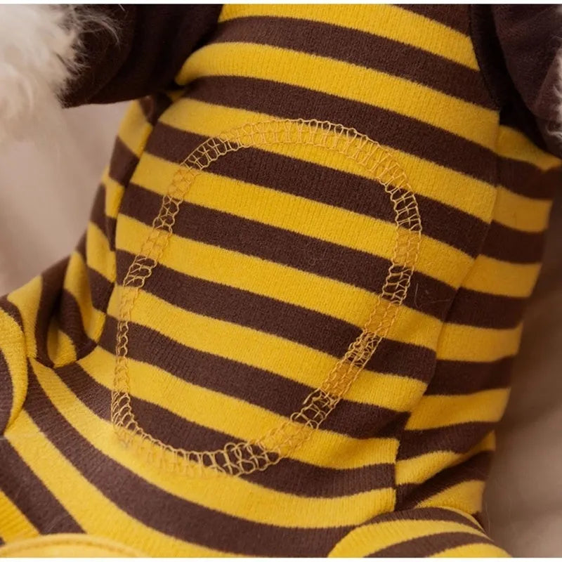 Yellow dog pajamas with bee pattern and lapel on small dog standing indoors