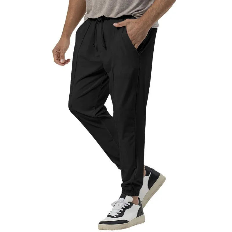 Man wearing grey tapered straight-leg casual sweatpants with a mid-rise elastic waistband.
