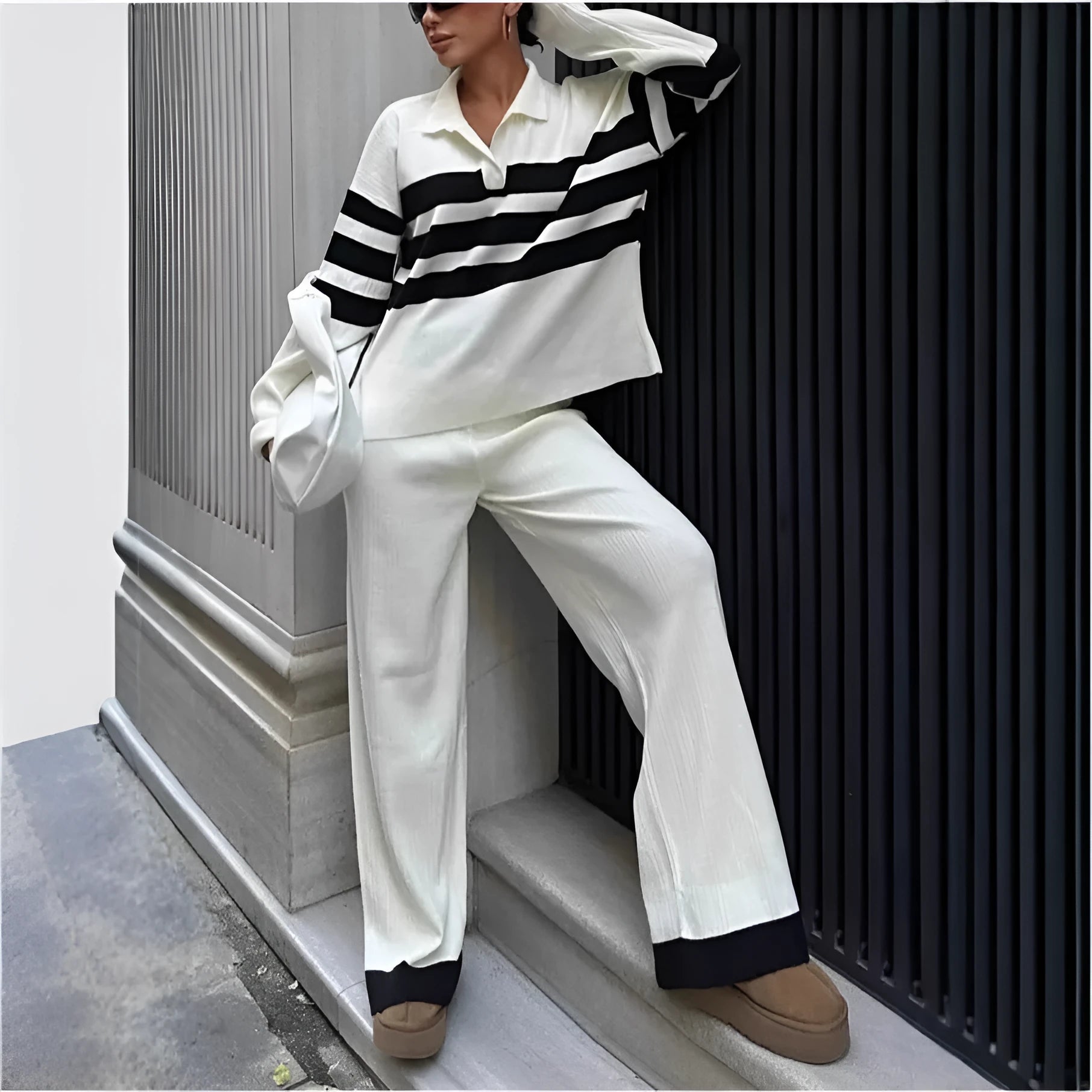 Women's black and white striped knitted two-piece set with polo collar top and full-length trousers.