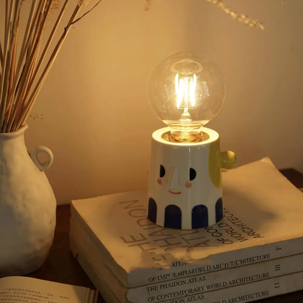 Handmade ceramic table lamp with white spherical shade on a wooden surface.