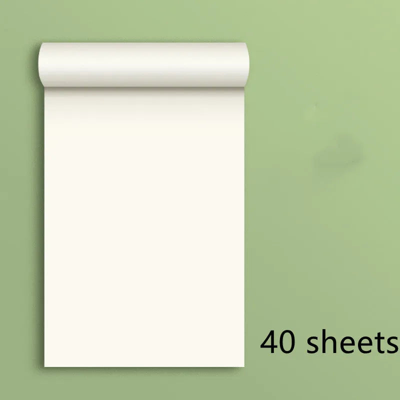 A4 blank draft notebook with picture colour cover, open to show unlined pages, placed on a desk with a pen.
