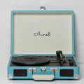 Cream-coloured retro phonograph in leather-effect suitcase with record on turntable and handle visible