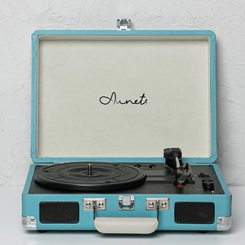 Cream-coloured retro phonograph in leather-effect suitcase with record on turntable and handle visible