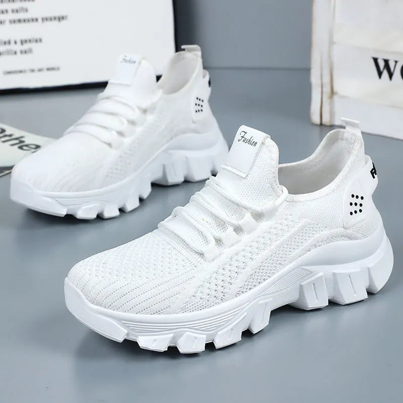 Women's white Flyknit running sneakers with a round toe and flat PVC sole, shown with lace-up front.
