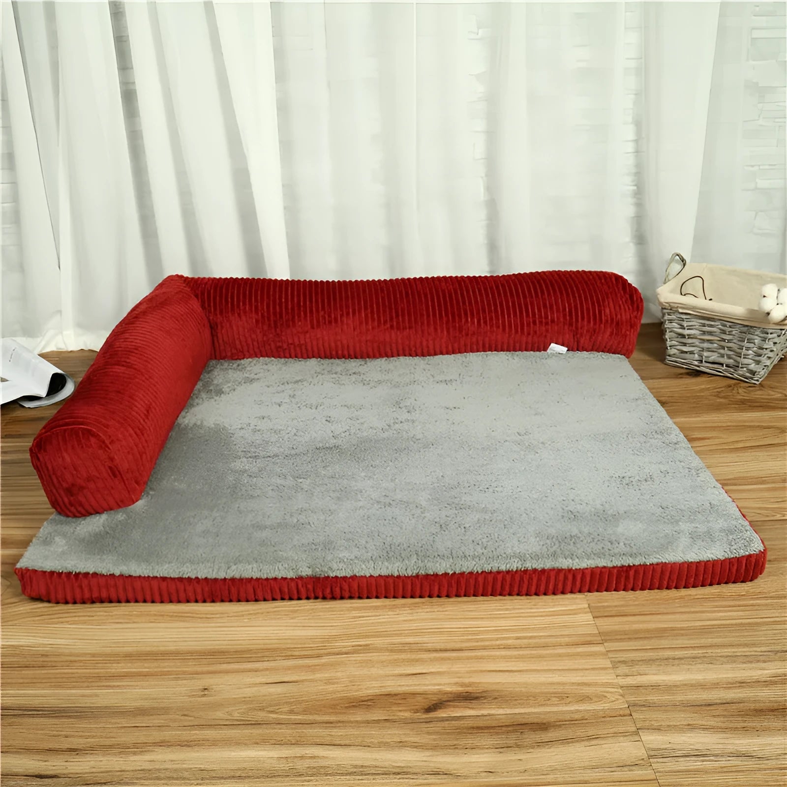Grey corduroy dog sofa bed with raised sides and a non-slip base on a wooden floor.