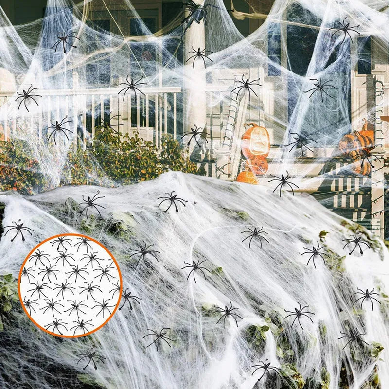 White cotton Halloween spider web decoration draped on a surface with scattered plastic spiders.