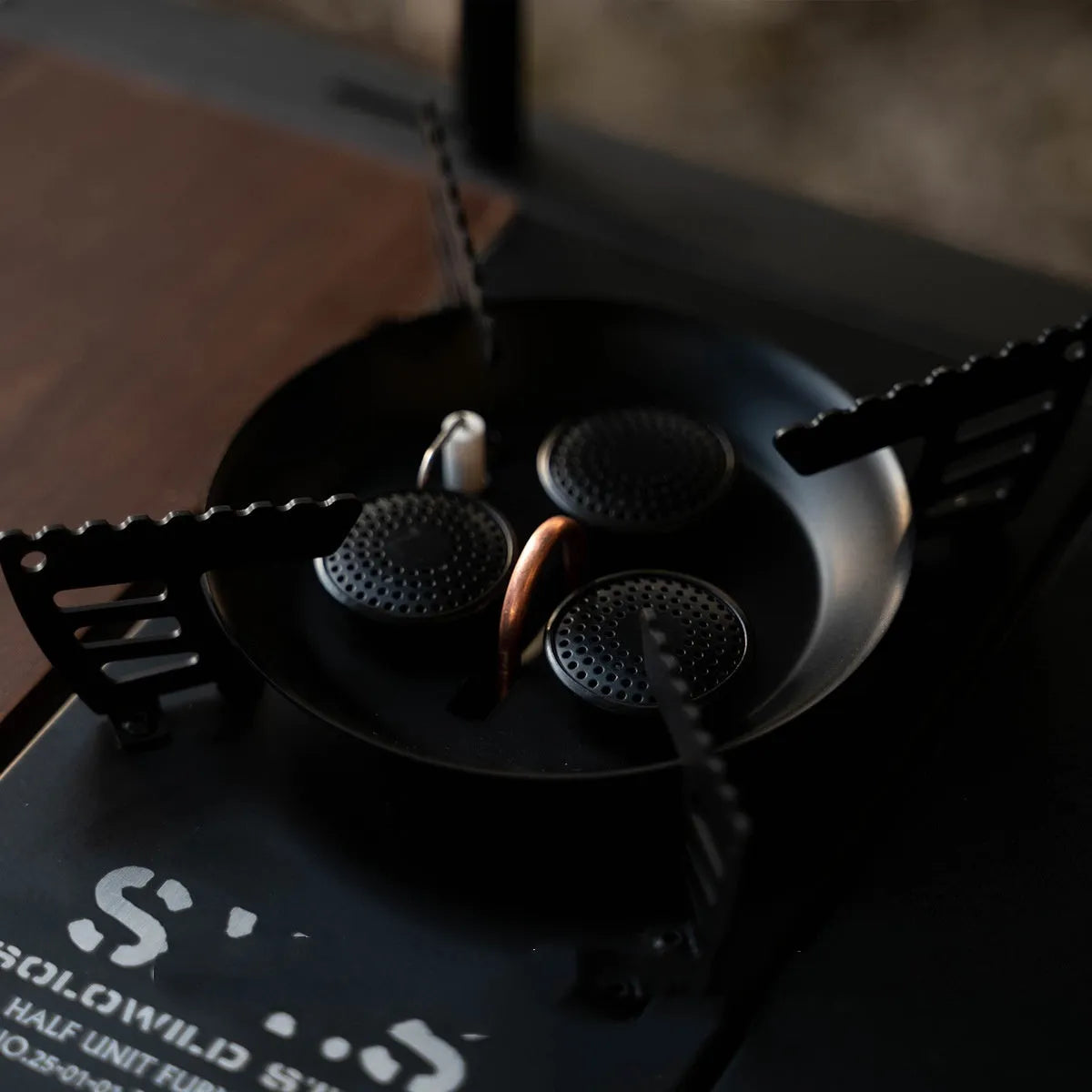 Black three-head split camping stove on outdoor table with burners visible