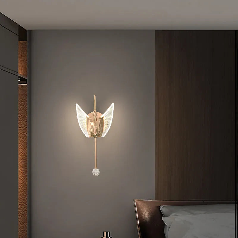Gold modern minimalist swan-shaped LED wall lamp with an acrylic shade on a wall.