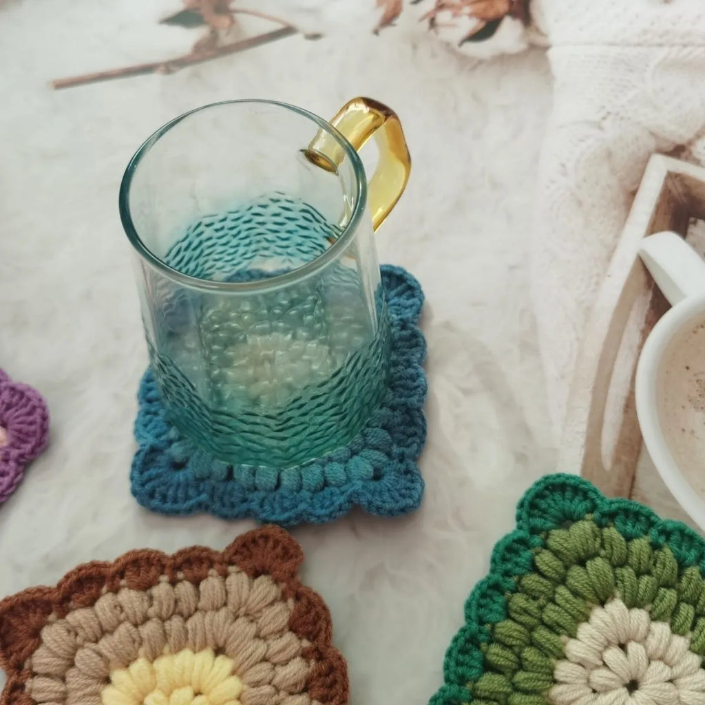 Hand crocheted wool cup coaster in Grandmother Lattice pattern, colour options include Emerald, Sea Salt Blue, Dream Purple, and Fog Brown.