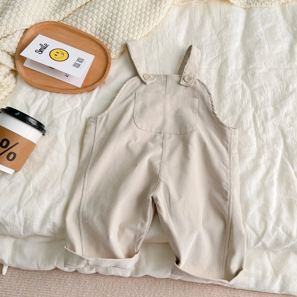 Unisex corduroy suspender overalls in creamy-white or brown plaid, with large pockets and double-breasted closure, for spring and autumn.