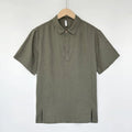 Man wearing a light grey green linen short-sleeve top with thin lapels and a loose fit.
