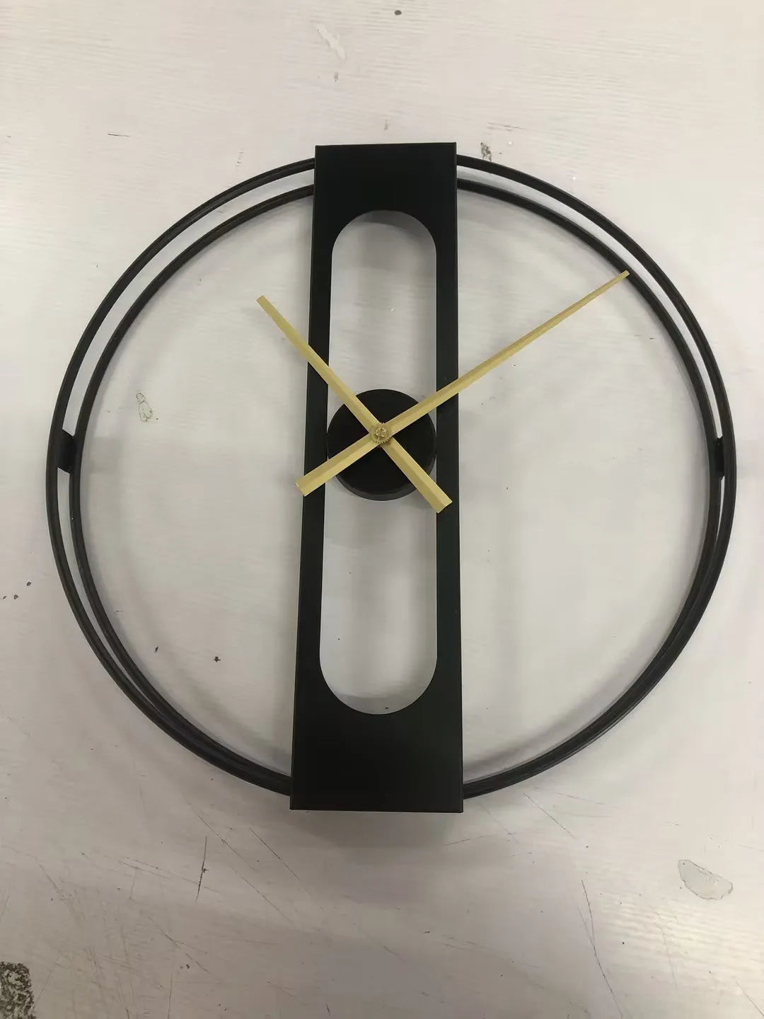 Round metal wall clock with 50cm diameter in black or gold finish on a wall