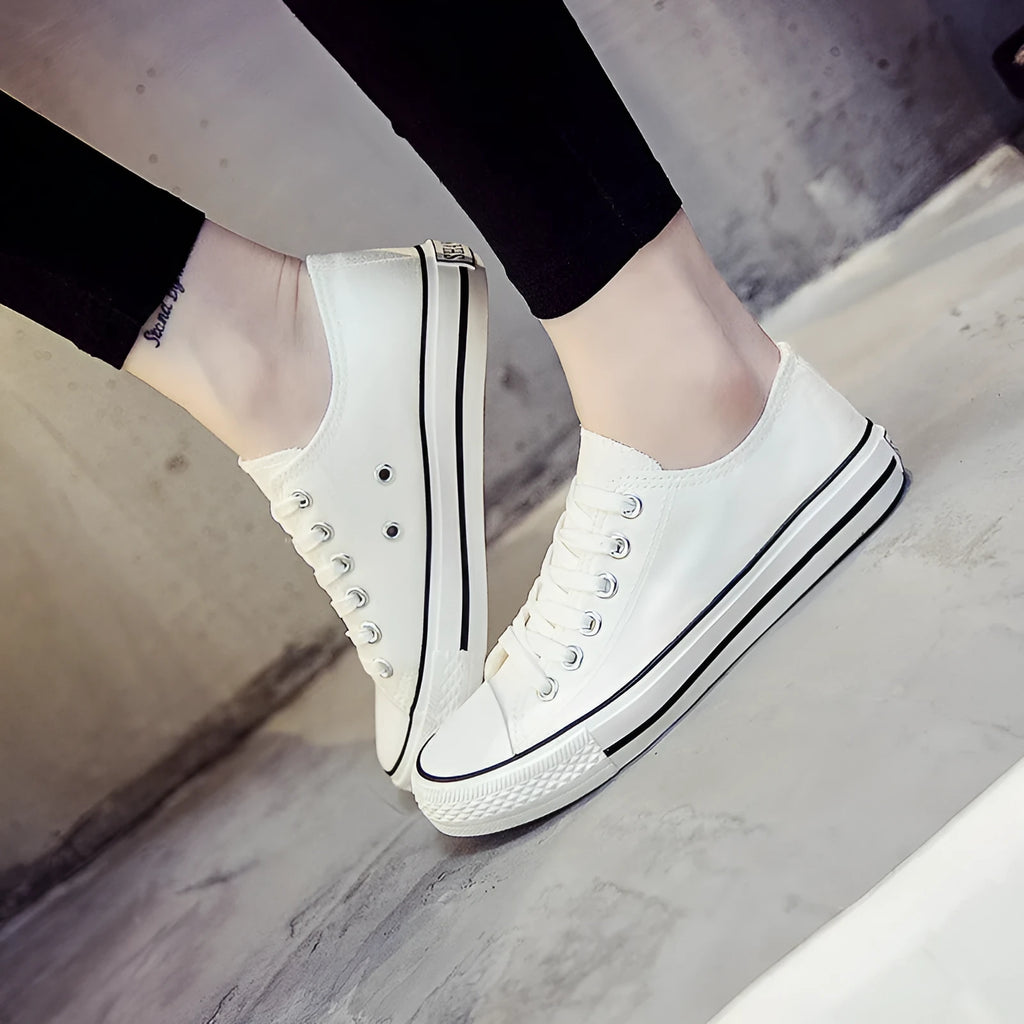 A pair of solid colour canvas lace-up trainers for women on a summer background.