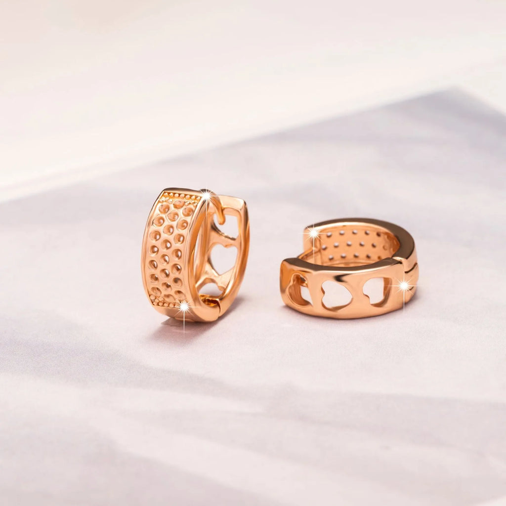 A pair of rose gold hollowed-out heart earrings on a white background, showing three-dimensional openwork detail.