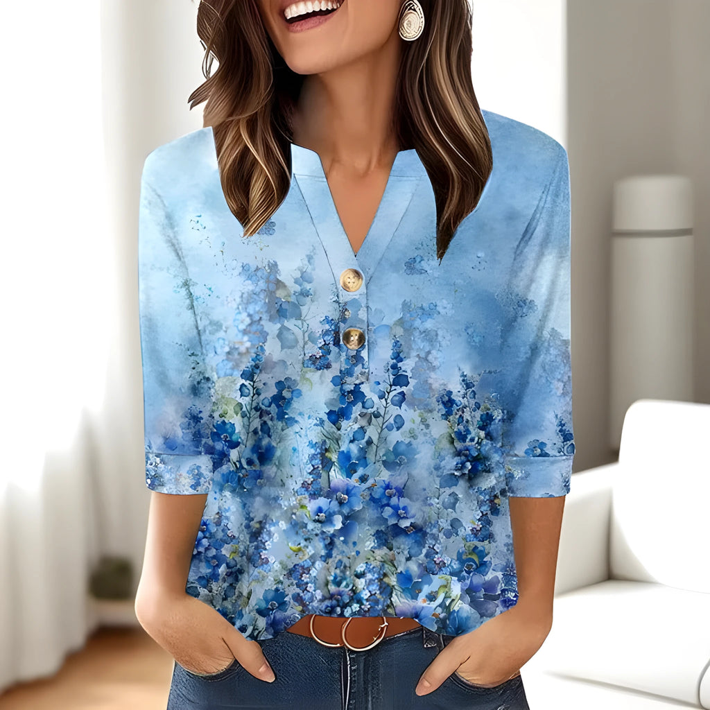 Woman wearing a loose-fit grey V-neck t-shirt with a colourful 3D geometric print, short sleeves.