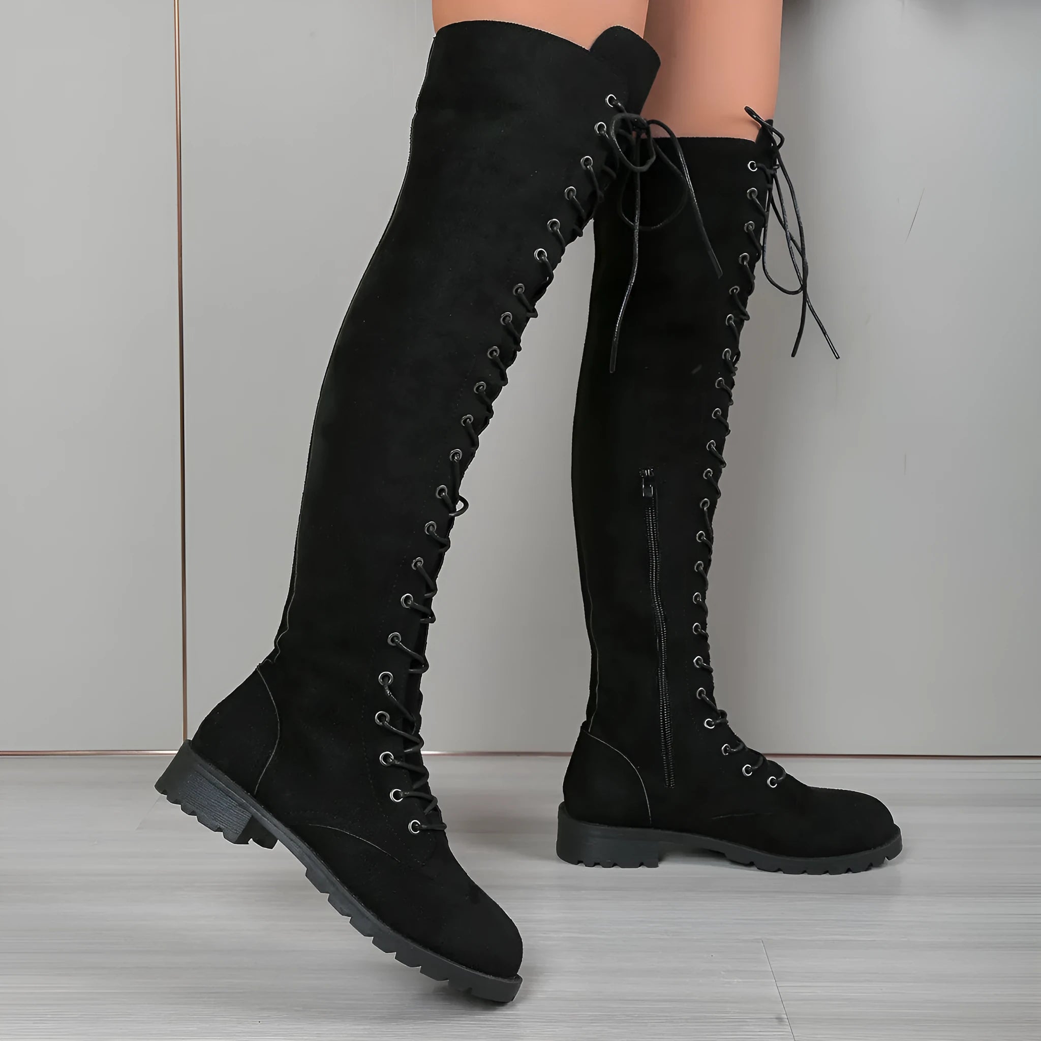 Women's black lace-up over-the-knee boots with stitching detail on a flat rubber sole, shown from the side.
