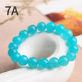 Loose natural Amazonite beads in ice blue colour, showing polished surfaces and irregular scattered shapes next to a finished bracelet.
