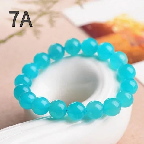 Loose natural Amazonite beads in ice blue colour, showing polished surfaces and irregular scattered shapes next to a finished bracelet.