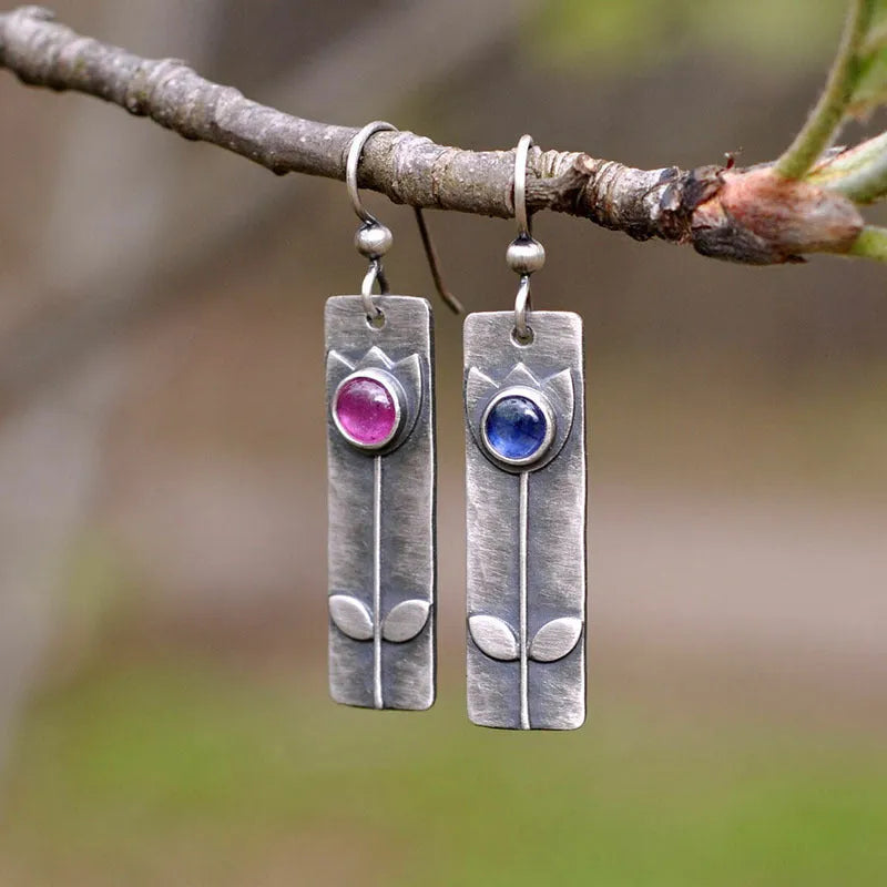 Pair of antique finish red sapphire geometric ellipse earrings with retro style on a white background.