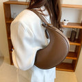 Retro-style dumpling-shaped PU leather shoulder bag in cream yellow showing front sandwich pocket.