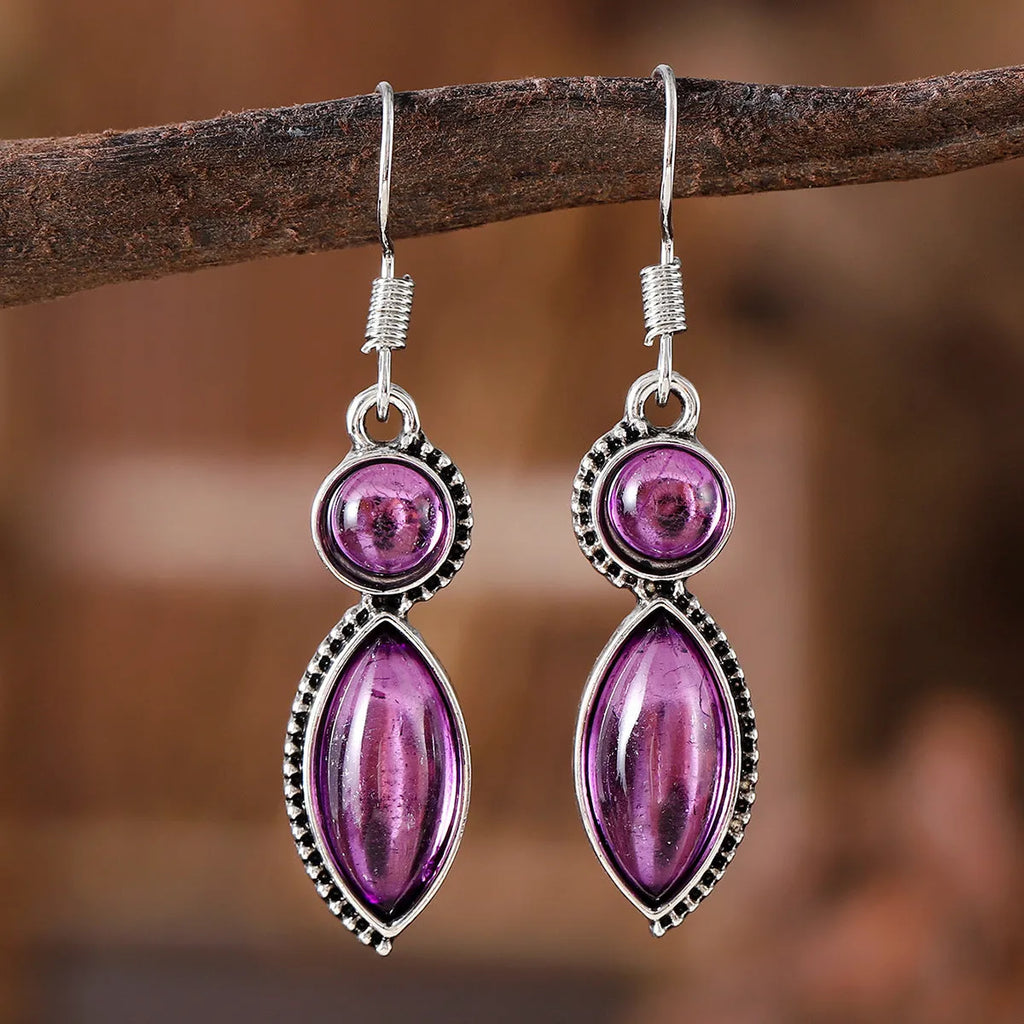 A pair of vintage-style geometric drop earrings with black and purple electroplated pendants on a white background.