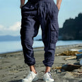 Men's solid colour linen trousers with ankle-tied cuffs, drawstring waist, and multiple pockets.