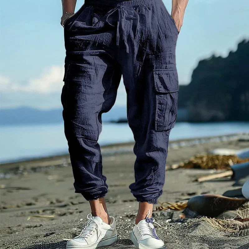 Men's solid colour linen trousers with ankle-tied cuffs, drawstring waist, and multiple pockets.