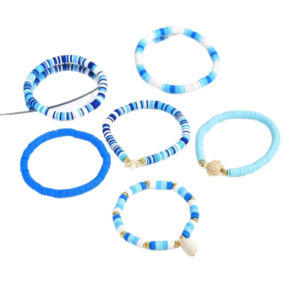 Six handmade Bohemian blue polymer clay bracelets with shell designs and geometric shapes arranged together