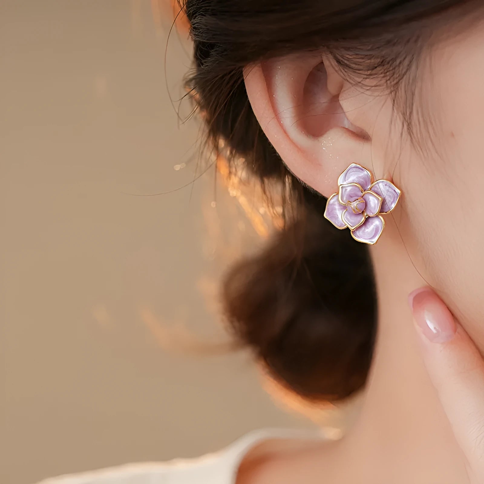 A pair of gold-plated purple flower stud earrings with a mottled oil-spot glaze on a copper base.