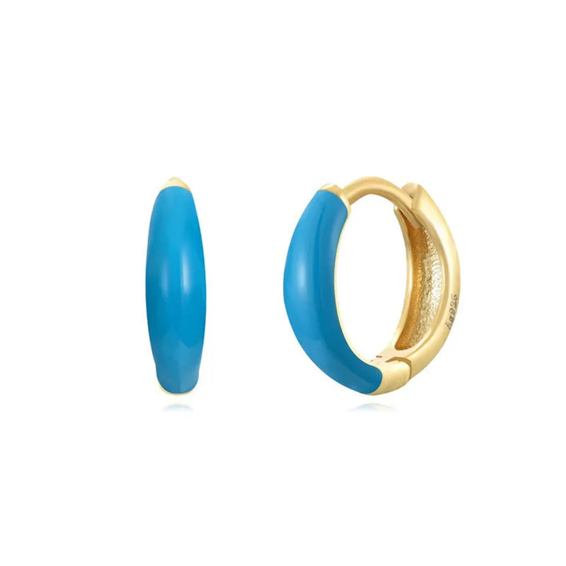 A pair of glossy light green epoxy oval earrings with a U-shaped curve and silver-coloured post on a grey background.
