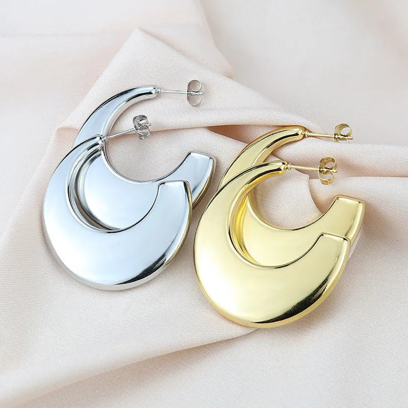 Two pairs of geometric thread stud earrings in gold and steel colour on a flat surface
