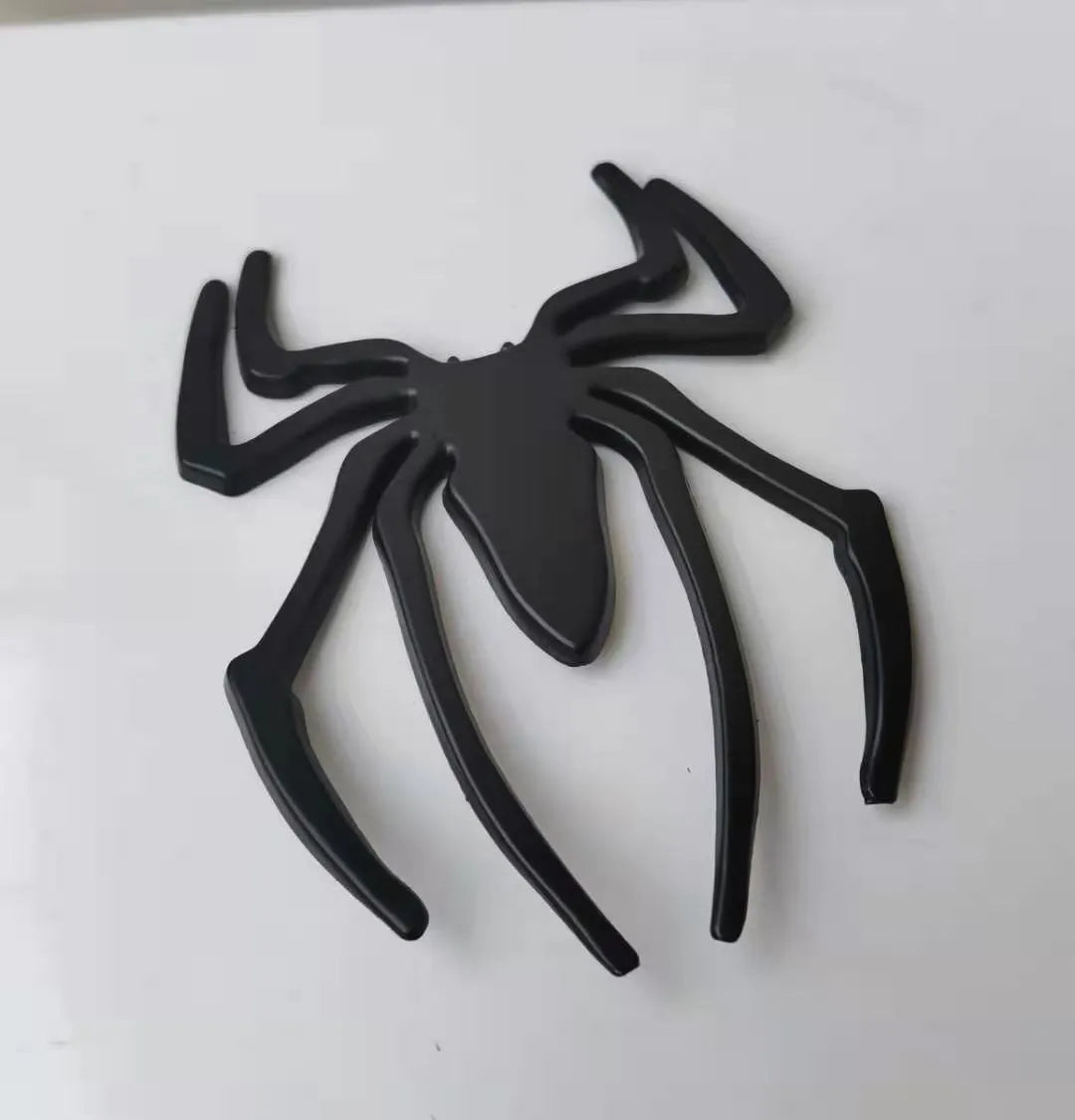 Three-dimensional metal spider bumper sticker in gold colour on vehicle surface