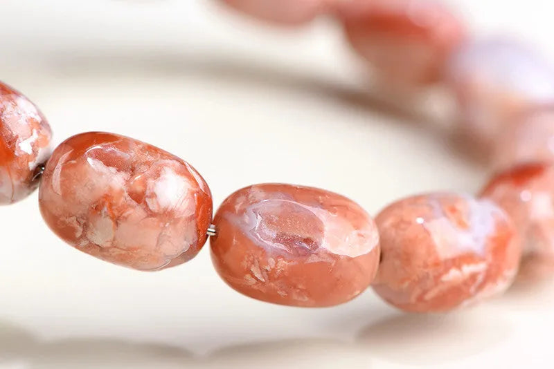 Natural cherry agate bracelet with barrel-shaped beads and a Ruyi design element on a wrist.
