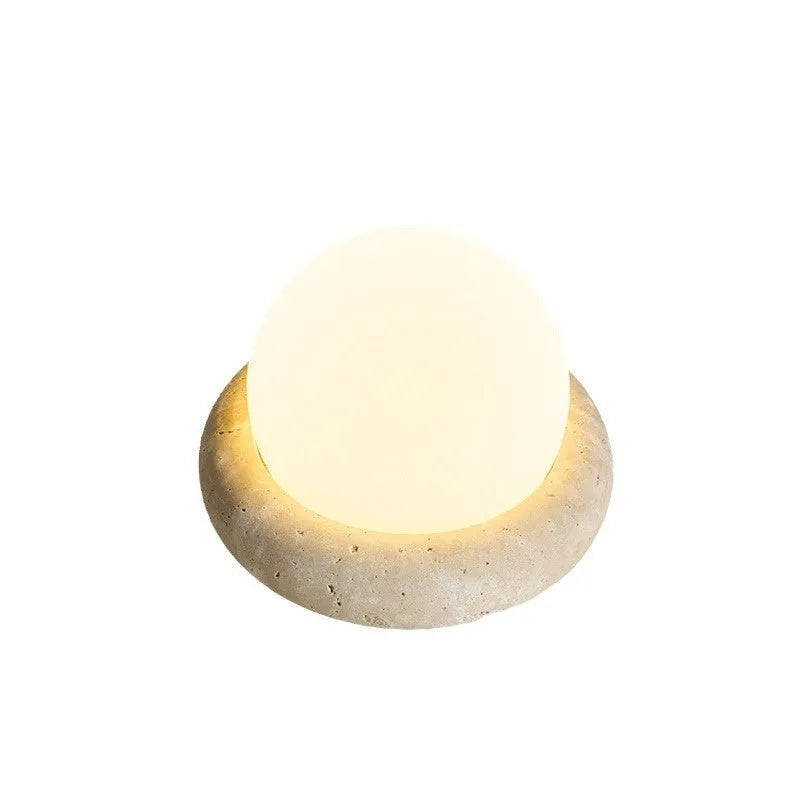 Circular modern night light with remote control on a wooden bedside table.
