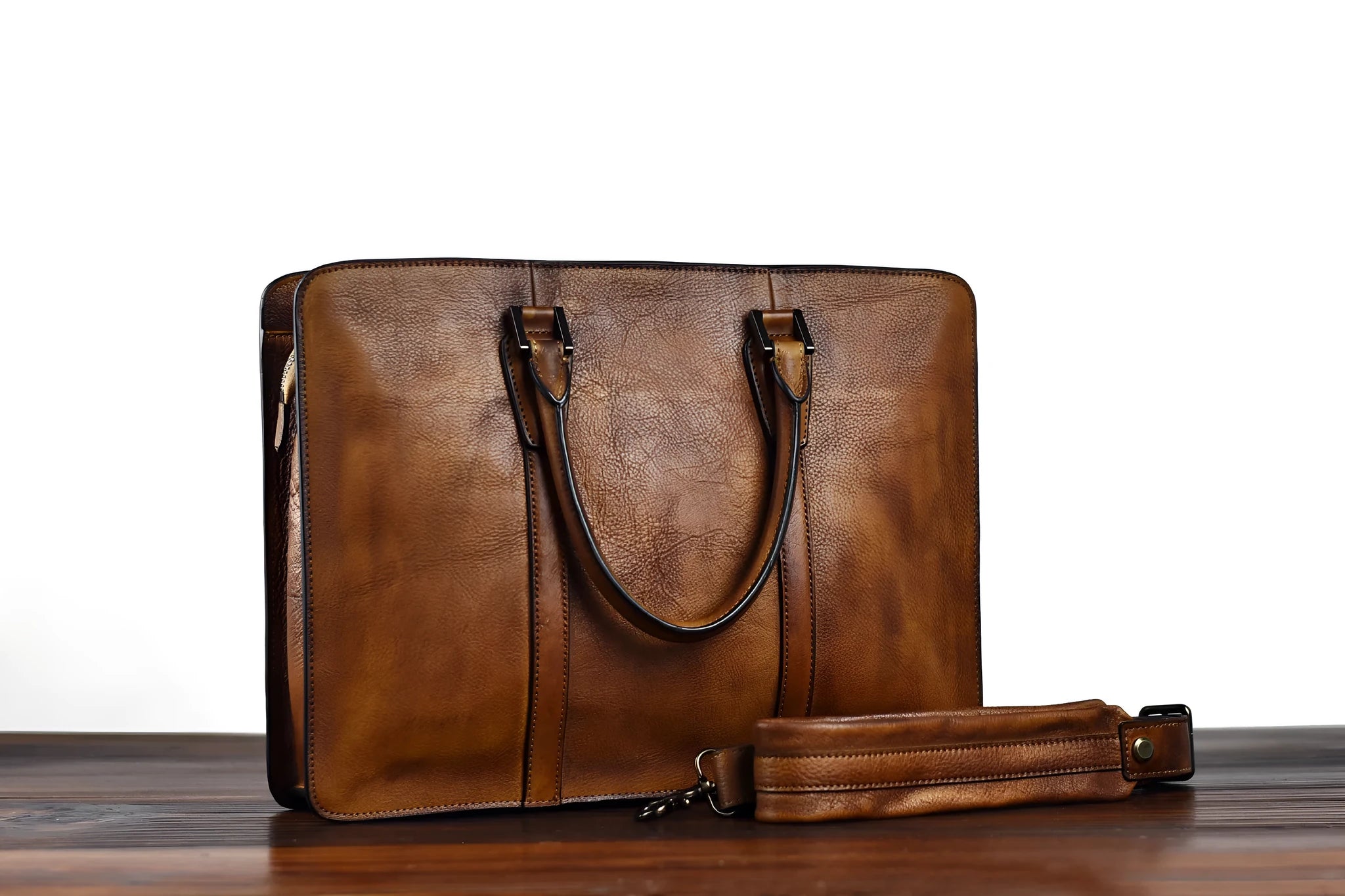 Men's brown leather horizontal business handbag with zipper, shown next to a 14-inch laptop for scale.