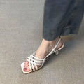 Beige retro women's sandals with thin crossing straps, an ankle buckle, and a 3-6cm mid-heel on a rubber sole.